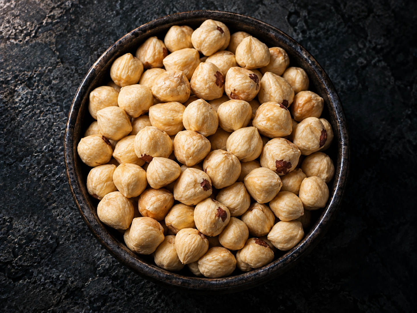Whole hazelnuts with skin in a dark bowl